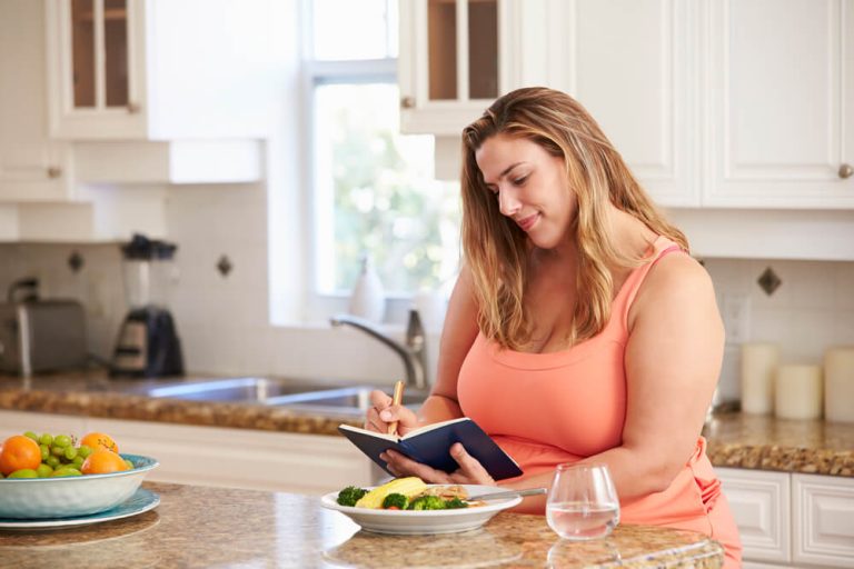 Woman in her kitchen, noting what she is about to eat