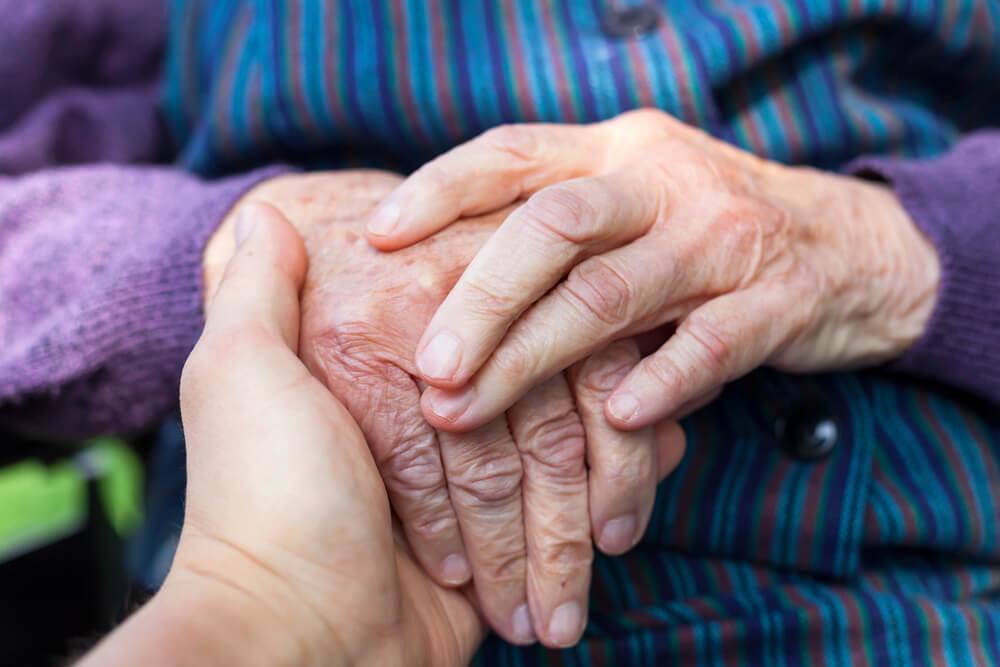 adult daughter comforting elderly mother