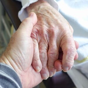 Adult son holding elderly mother's hand