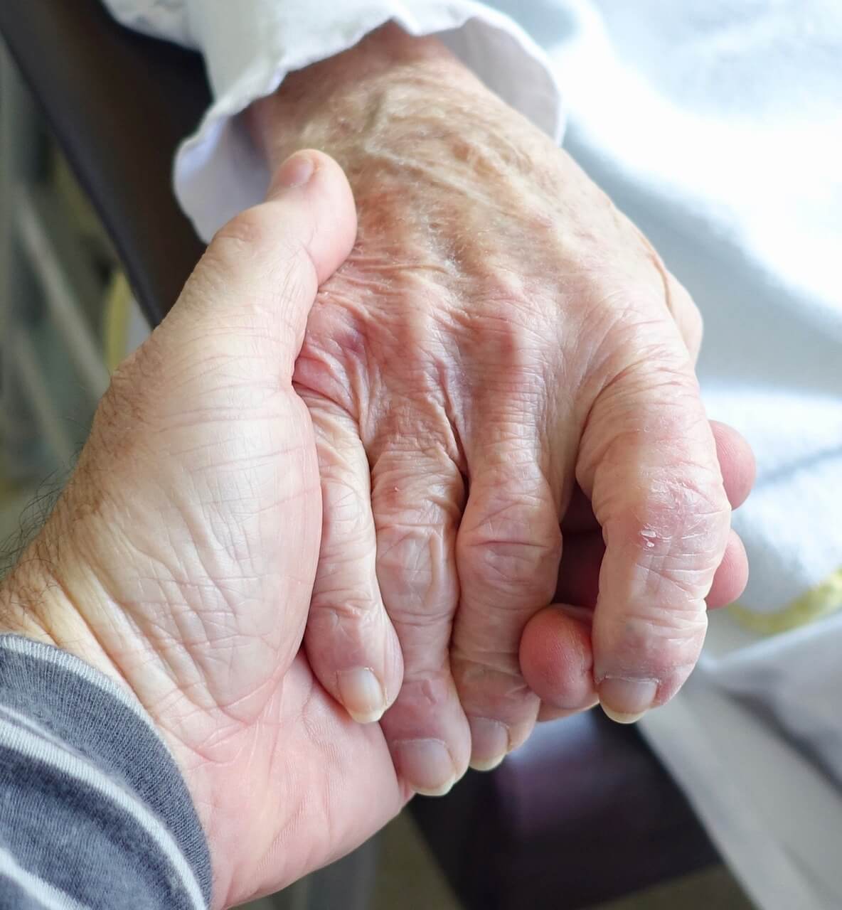 Adult son holding elderly mother's hand