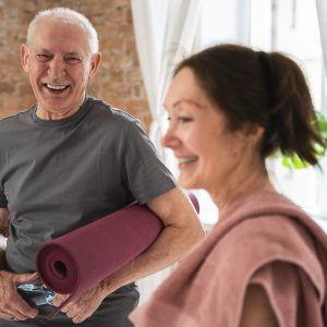 Two cheerful and active old people with exercising mats. Happy elderly couple ready for workout.