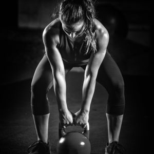 Woman athlete exercising with kettlebell indoors